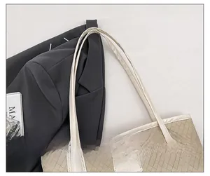 Detailed macro view of woven beige tote bag texture with slim leather shoulder straps
