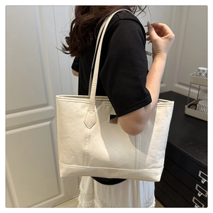 Close-up of white tote bag featuring cartoon dog embossing and metallic logo plate