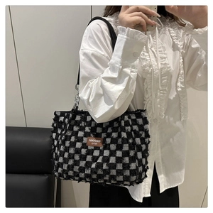 Detail of checkered canvas tote bag with fringed edges and a vintage leather patch