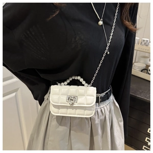 Close-up of white quilted mini bag with pearl handle and metal chain shoulder strap
