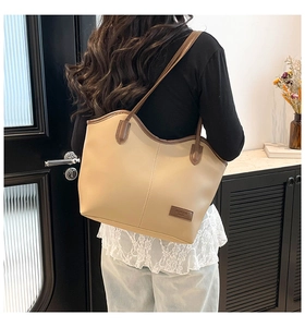 Detail of minimalist beige tote bag with brown straps shown on shoulder for commuting