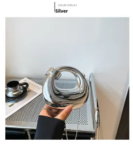 Detail of silver mirror finish mini handbag with metallic chain and sleek curved handle