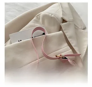 Close-up of pink leather strap and woven fabric texture on a crescent shoulder bag