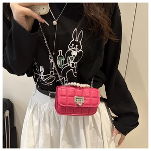 Close-up of rose pink quilted mini crossbody bag with pearl handle and metal chain