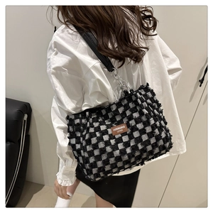 Detail of checkered tote bag with frayed edges and leather strap with metal chain