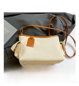 Dettaglio della trama tessuta color crema e rifiniture in pelle marrone della borsa