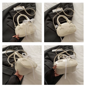 Detail view of cream-white shell bag featuring 3D bow design and lace ribbon details