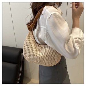 Beige woven hobo bag with brown leather knotted strap worn by a model on shoulder