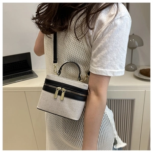 Detail of canvas crossbody bag with black leather trim and elegant gold hardware