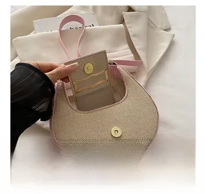 Detail of pink leather trim, beige woven texture and golden magnetic buckle on crescent bag