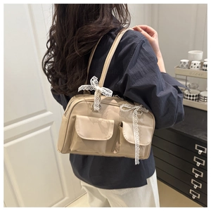Détail du sac à bandoulière beige avec nœuds en dentelle et deux poches à rabat devant