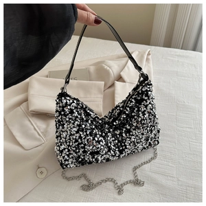 Detail of sequined handbag featuring metallic chain strap and black leather handle