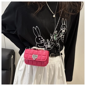 Detail of fuchsia quilted mini bag with pearl handle and silver chain strap on model
