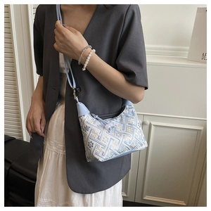 Detail of light blue geometric embroidery and silver hardware on a crossbody bag