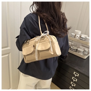 Close-up of beige PU leather shoulder bag with front flap pockets and lace bow detail