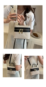 Detail view of canvas and leather box bag with dual gold zippers and adjustable strap