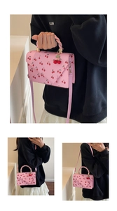 Detail of pink cherry print handbag featuring envelope flap and 3D cherry charm