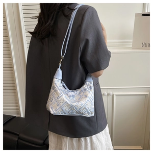 Detailed view of a light blue hobo bag with geometric embroidery on a female model