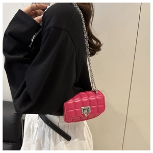 Detail of rose pink quilted mini crossbody bag with silver chain strap on model