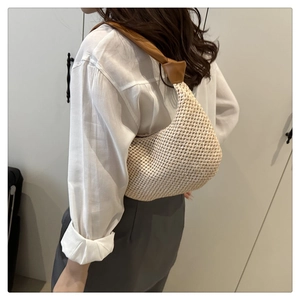 Detail of hand-woven beige tote with brown leather strap and elegant knot design