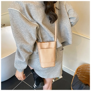 Detail of beige pebble leather mini bucket bag with front pocket and slim strap