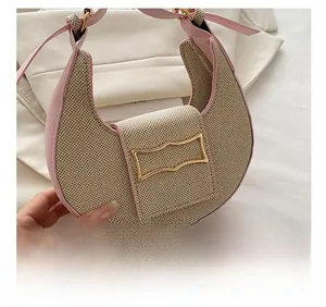 Detailed view of beige woven fabric with pink leather trim and gold metal buckle