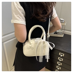 Rear view of a model carrying a white semi-circular lace bag with bow stitching detail