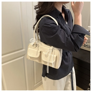 Detail of off-white leather shoulder bag featuring lace bows and double front pockets