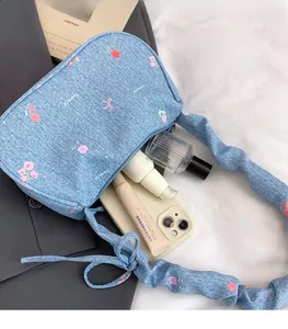 Detail view of denim underarm bag showing spacious storage for phone and cosmetics