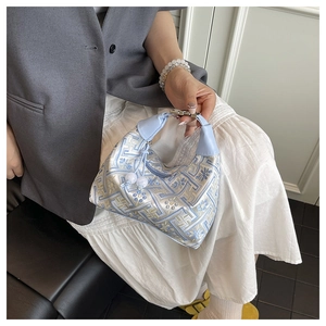 Detail of light blue brocade shoulder bag with floral embroidery and metallic clasp