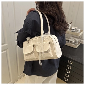 Détail du sac Boston blanc crème avec rubans en dentelle et petites poches à rabat