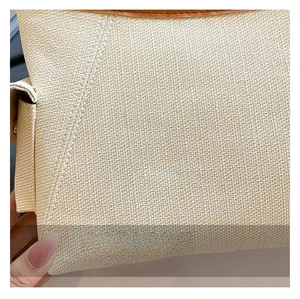 Dettaglio della trama in tessuto beige e bordino in pelle marrone della borsa