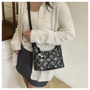 Detail of black cross-body bag with white geometric embroidery and bead tassel zipper