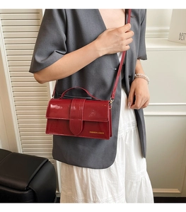 Detail of the dark red glossy patent leather shoulder bag with gold brand lettering