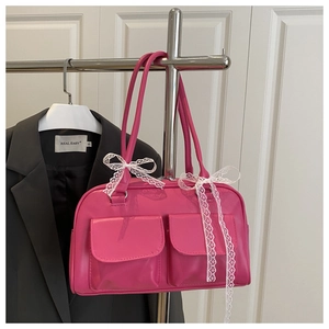 Close-up of hot pink leather handbag featuring dual front pockets and lace bow detail