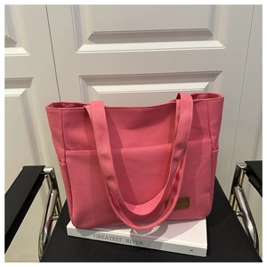 Detailed close-up of pink canvas tote bag with brown leather tag and side pockets