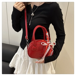 Red glossy shell bag with embossed bow and lace ribbon detail shown as a crossbody