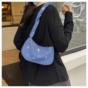 Detail of denim shoulder bag with floral embroidery and ruched strap design