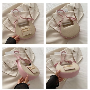 Detail of a pink leather and beige fabric half-moon bag with golden wave buckle and slim strap