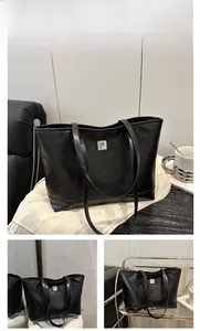 Detail of black tote bag with embossed cartoon animals and square metal logo