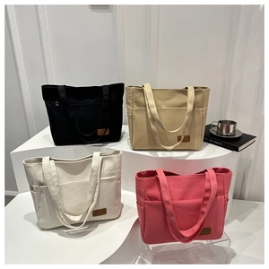 Detailed view of large canvas tote bags in four colors arranged on a white display stand