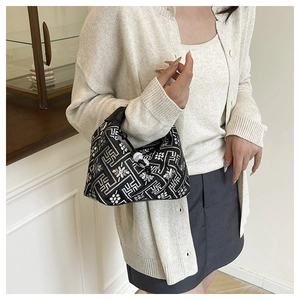 Detail of a black moon-shaped handbag featuring white geometric patterns and floral motifs