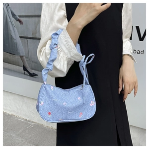Detail of light blue floral fabric bag with ruffled strap and ribbon bow decoration