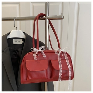 Detail of red vintage boston bag featuring front flap pockets and white lace bow decor