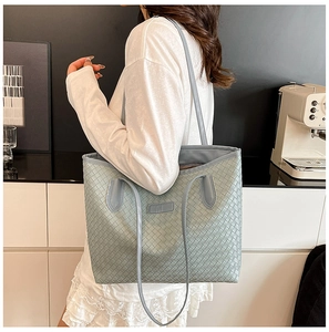Detail of light blue woven PU leather tote bag showing large square weave and slim shoulder straps