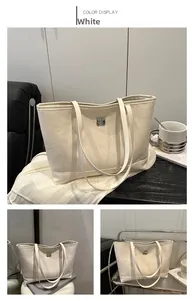 Detailed view of white tote bag featuring embossed heart patterns and silver metal buckle