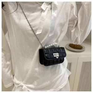 Detail of black quilted crossbody bag with pearl handle and silver chain strap