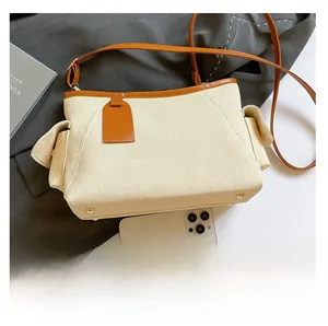 Vista dettagliata della borsa tote intrecciata beige con finiture in pelle marrone e telefono