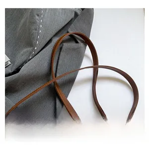 Detailaufnahme des braunen Leder-Schultergurts mit feiner Naht an weißer Tasche