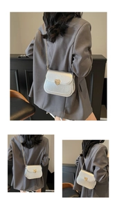 Detail of silver patent leather crossbody bag with golden heart buckle and chain strap